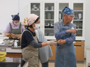 左側の受講生が手にした桜の葉の塩抜き加減をチェックする講師