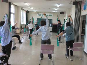 ゴムチューブを持ち、手を上にあげ左右に体を曲げて肩甲骨を刺激します