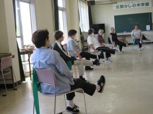 椅子に座って片足ずつ交互にまっすぐに上げる運動をする様子