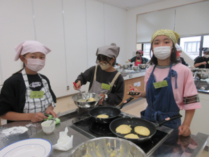 ２つのコンロで順番にパンケーキを焼く受講生の子ども達
