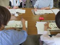 筆ペンで大きい丸や小さい丸を書く練習をしている様子