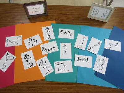 完成した作品を赤やオレンジの色画用紙の上に並べて披露している様子