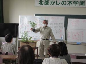 受講生の前で植物を手に講義する講師の様子