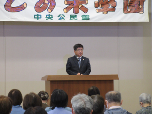 ステージ上の演題前に立ち、挨拶される菅野教育長