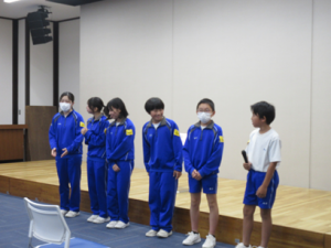 会場正面に６人並んで感謝の言葉を述べる中学生