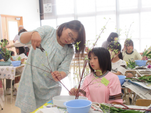 子ども達の横に立ちはさみの入れ方を実演する講師