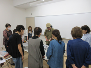 受講生を教壇まわりに集め中央で縫い方のコツを教える講師先生