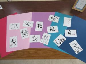 花や夢など好きな一文字を書いた作品を色画用紙の上に並べて披露している様子