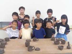 台の上にみんなの作品を置き、講師先生と午後の参加者の記念写真