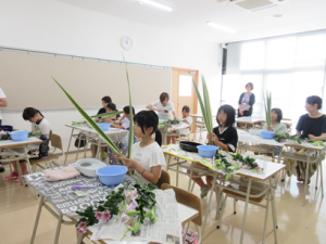 主格となるニューサイランを手に生け花の中心を決める葉を選ぶ受講生