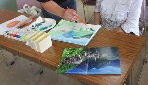先生に「山の中にある教会の風景画」の山の緑色ついて指導を受けている様子