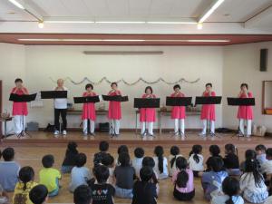 座る子どもたちの前に8名並んでオカリナ演奏をしている様子