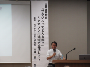 写真中央に講師先生、後方には演題を記した垂れ幕