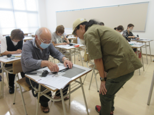 作業に手間取っている受講生のもとへ行き説明する講師先生