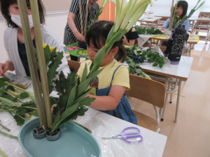 子どもの達の横に座り一緒に生け花を楽しむ保護者の皆さん
