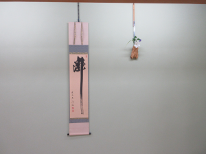 瀧と書かれた掛け軸と蝉の形をした竹籠に生けられたお茶花