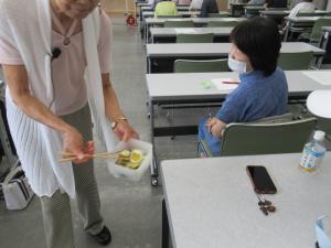 炊き込みご飯を作る際に一緒に卵や野菜を入れると簡単に一品が出来ると講師が受講生に見せて説明しているところ