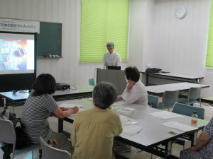 講師が前方のスクリーンに書類の片付けの実例写真を写して受講生に説明しているところ