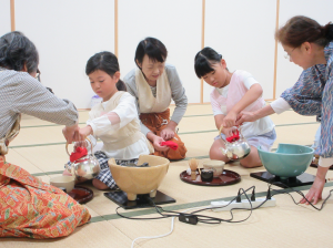 お茶のたて方をマンツーマンで教えてもらっている子ども達