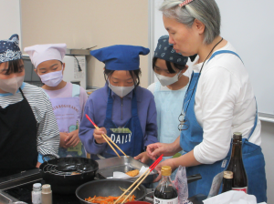 揚げ物で火傷をしないように実演して見せる講師先生