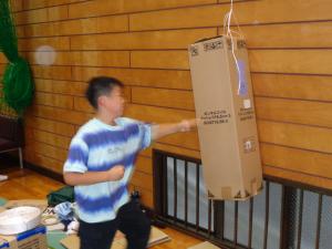 上からつるしたサンドバックをたたく男の子