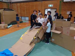 完成した滑り台でポーズをとる子どもと高校生スタッフ