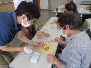 金箔職人と一緒に3センチ四方の薄い金箔を竹の箸でそっとつまんで張り重ねていく様子