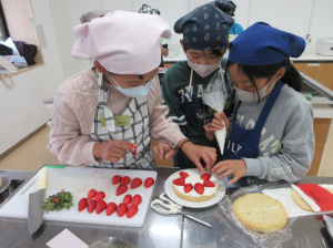 創意工夫しながらショートケーキをデコレーションする子ども達