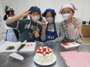 出来上がったケーキを前に満足げにピースサインをする子ども達