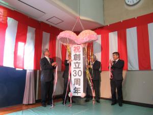 記念式典でくす玉がきれいに割れて拍手が起こっている様子