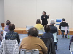 舞台上で寒い時期の筋肉のほぐし方を説明している講師