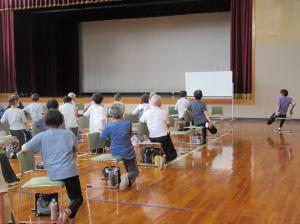 椅子に横向きに座り太もものストレッチ運動の指導をされる田中先生と講座生の様子