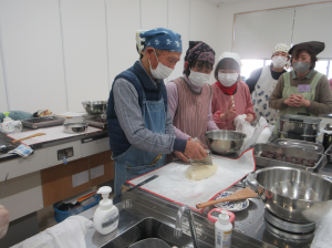 蒸しあがった餅かわの切り分け方の手本を見せる講師先生