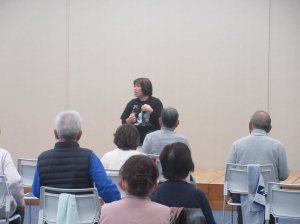 舞台に座り今日の運動のポイントを説明する講師先生