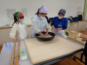 スタッフのアドバイスを受けそば粉をこねる女の子