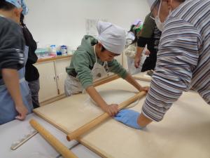 麺棒を使って生地を伸ば男の子