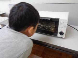 心配そうにトースターをのぞき込む男の子