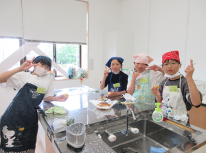 試食タイムで美味しく焼けたケーキを頬張りピースサインする子ども達
