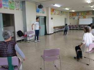 椅子に座り講師の動きに合わせて肩を動かす様子