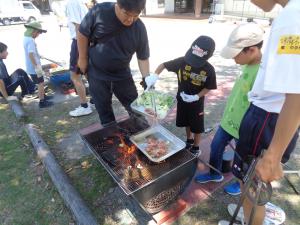 肉をプレートに入れ火を通す男の子の様子