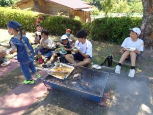 完成した焼きそばとご飯を木陰でおいしそうに食べる赤グループ