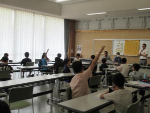 講師から出された問題に答えようと挙手をする複数の生徒