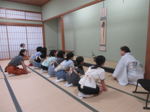 床の間の掛け軸並びにいけ花の説明を聞く受講生