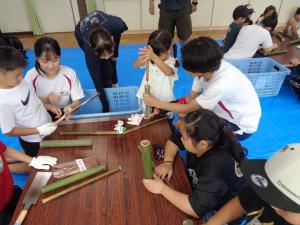 高校生スタッフに手伝ってもらいながら押し棒を作るこどもたち