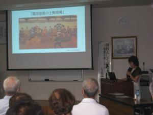 受講生の前で、プロジェクターで資料を投影して説明している講師