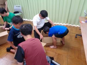 お父さんと一緒に段ボール砲を作る男の子
