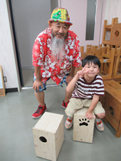 出来上がったカホンに座り嬉しそうな小学生と講師