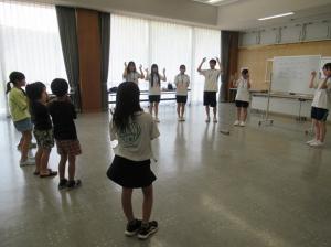 頭肩と手を動かしながら英語の歌を全員で歌う様子