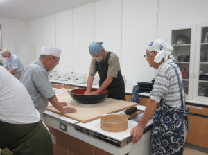 そば粉を捏ねる受講生と見守る麺々の皆さん