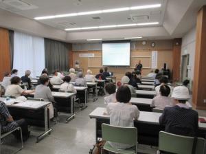 プロジェクターを使い講義をする講師と会場全体の様子